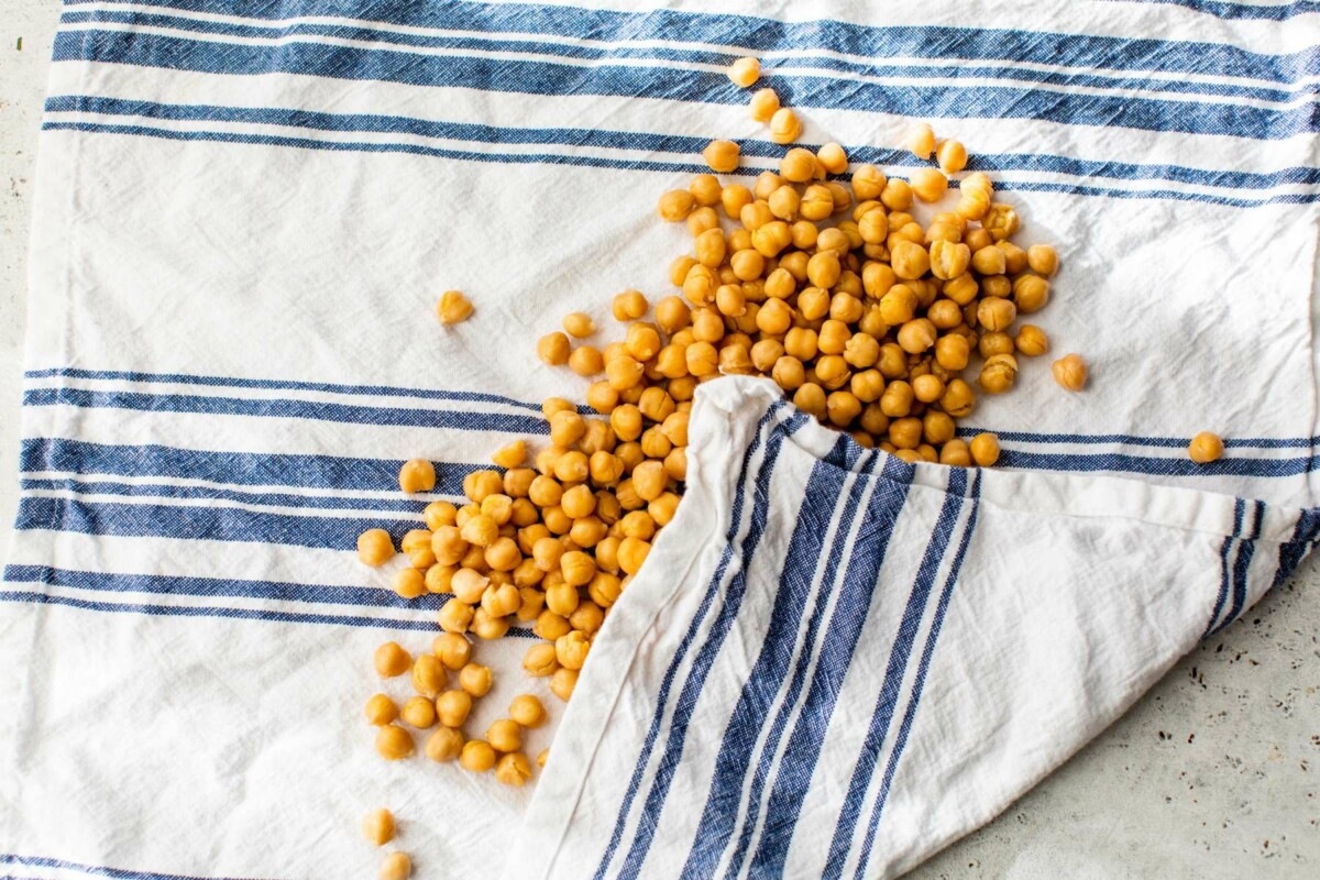 Patting chickpeas dry with a kitchen towel.