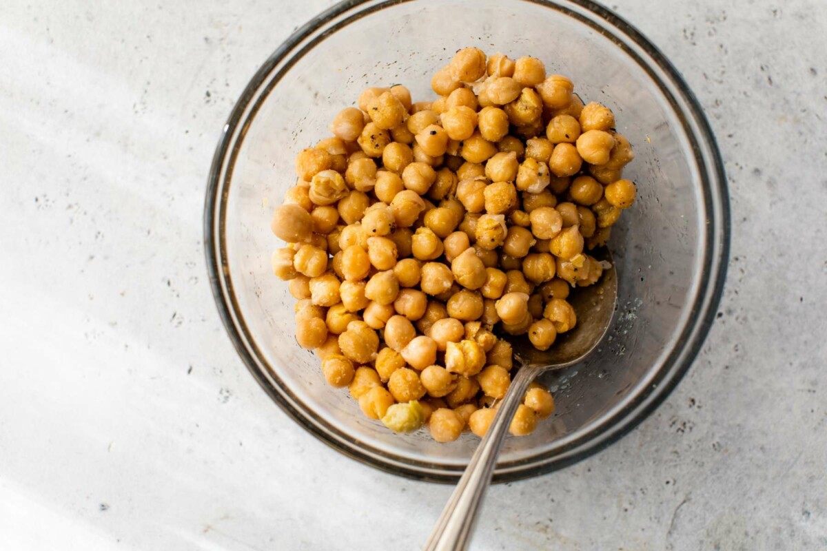 Seasoning chickpeas with oil, salt, pepper and garlic powder.