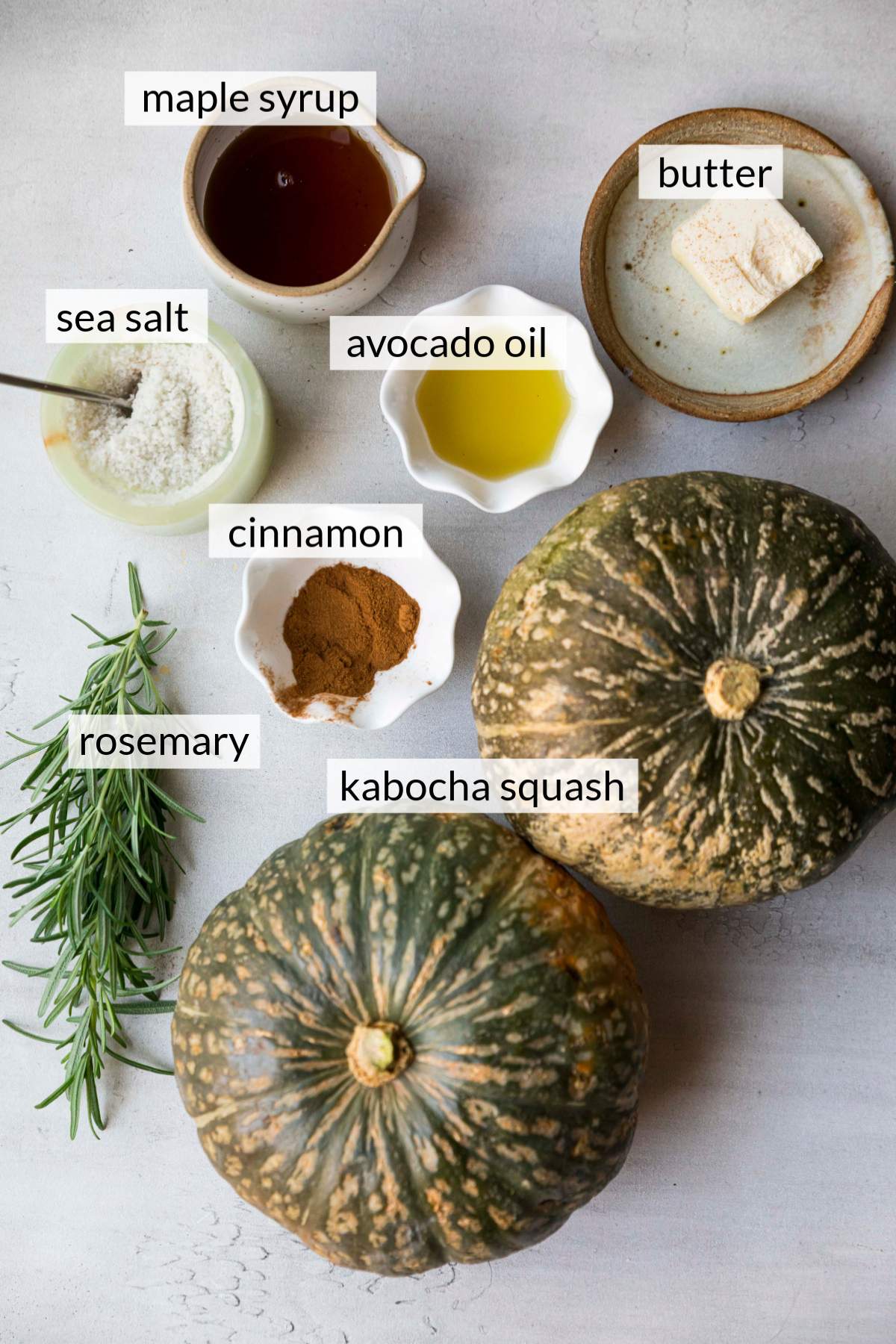 Kabocha squash near small bowls of oil, cinnamon, maple syrup and salt.