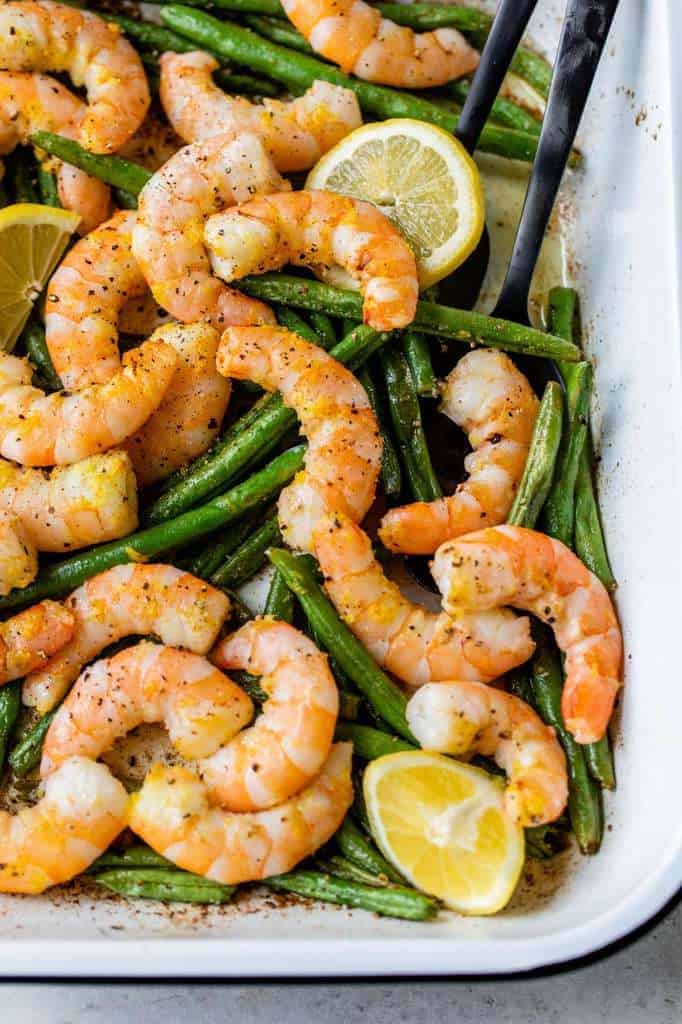 roasted shrimp and green beans in a white cooking dish 