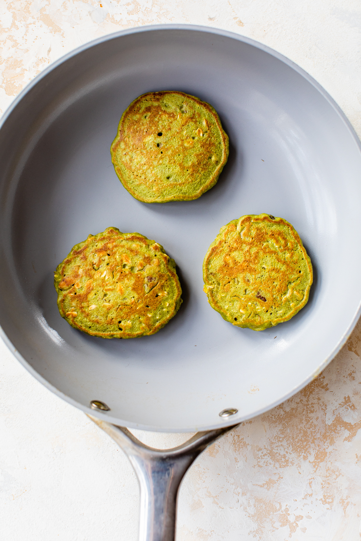 healthy spinach pancakes cooking in a non stick skillet