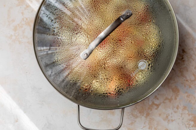Skillet with apples covered with a lid.