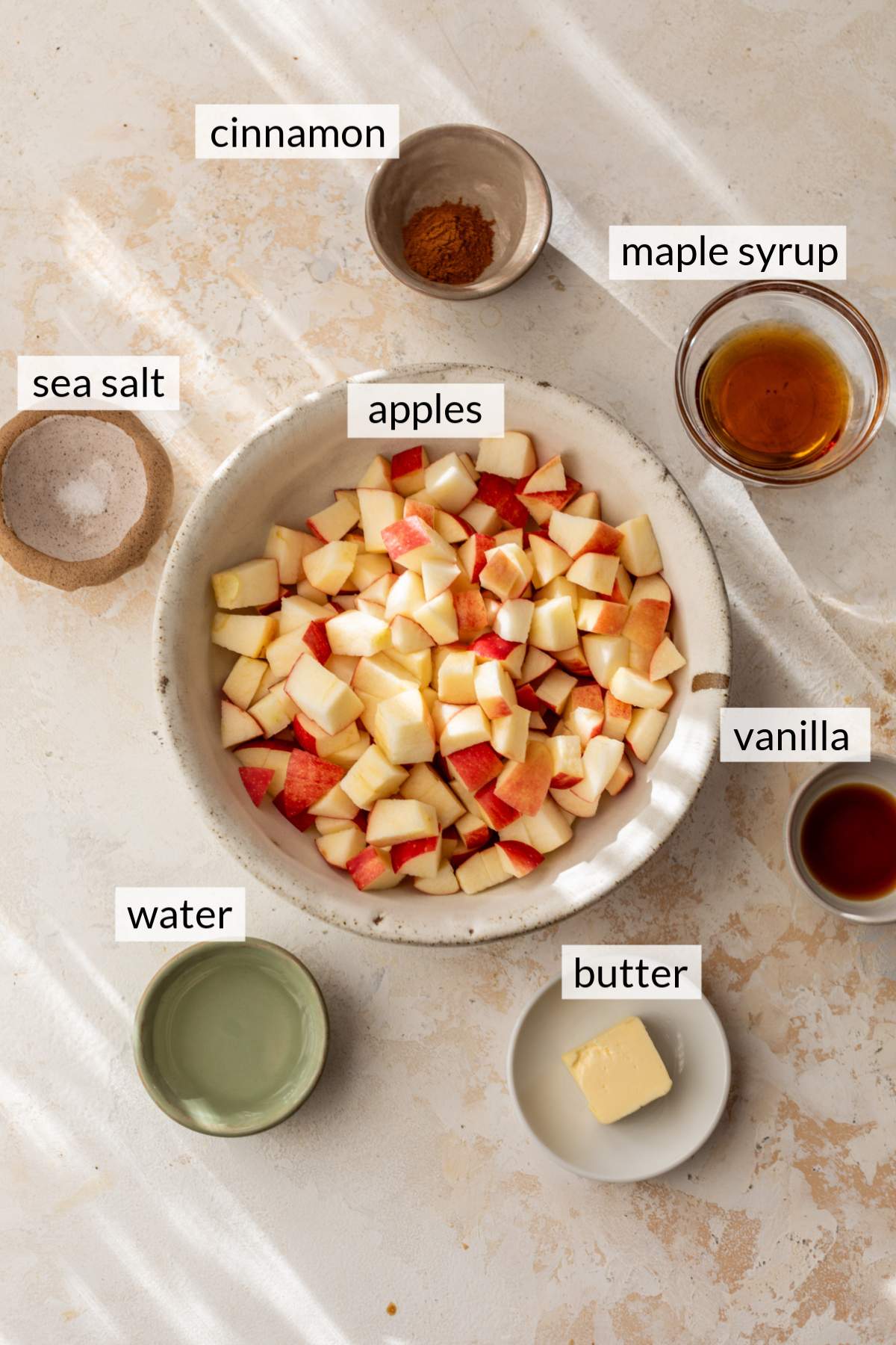 Bowls with chopped apples, cinnamon, butter, water, salt, vanilla and maple syrup.