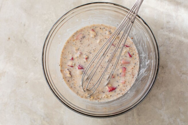 Whisking yogurt, milk, oats and strawberries in a bowl.