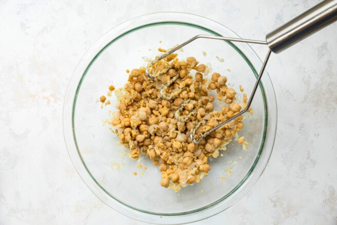 Mashing chickpeas in a bowl.