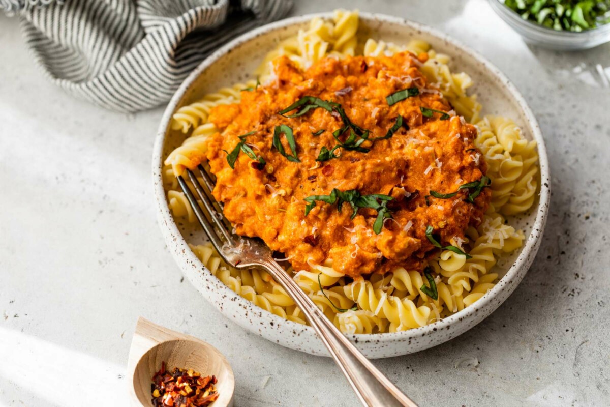 Turkey bolognese served over pasta on a white plate.