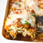 Serving a slice of turkey spinach lasagna out of a casserole dish.