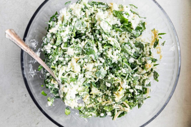 Mixing spinach with cottage cheese, eggs and parmesan cheese.