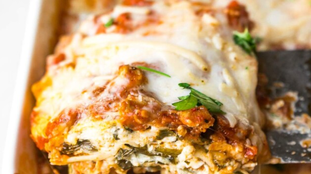 Serving a slice of turkey spinach lasagna out of a casserole dish.