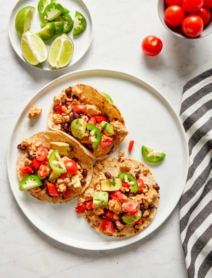 turkey tacos with black beans and bell pepper served in corn tortillas on a white plate
