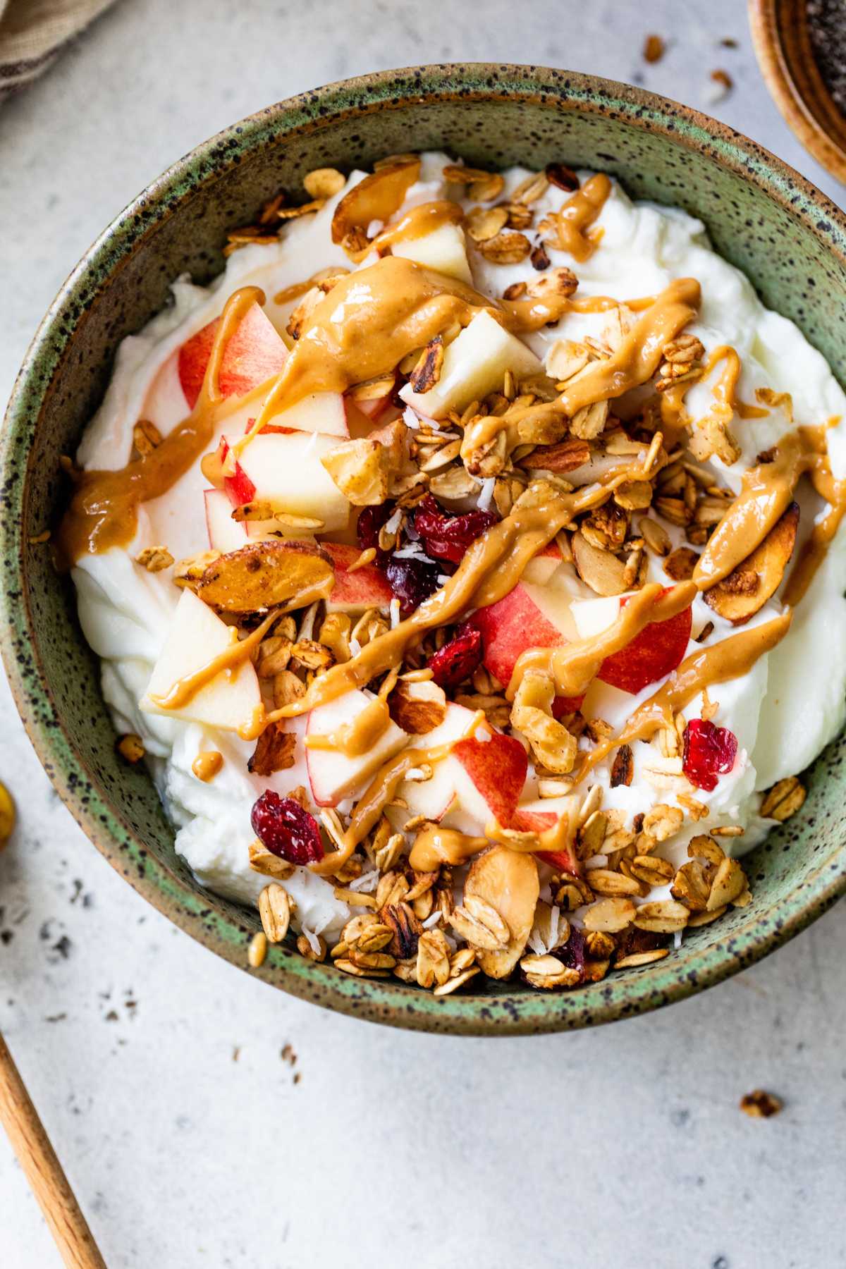 Bowl with yogurt, granola, apple and peanut butter.